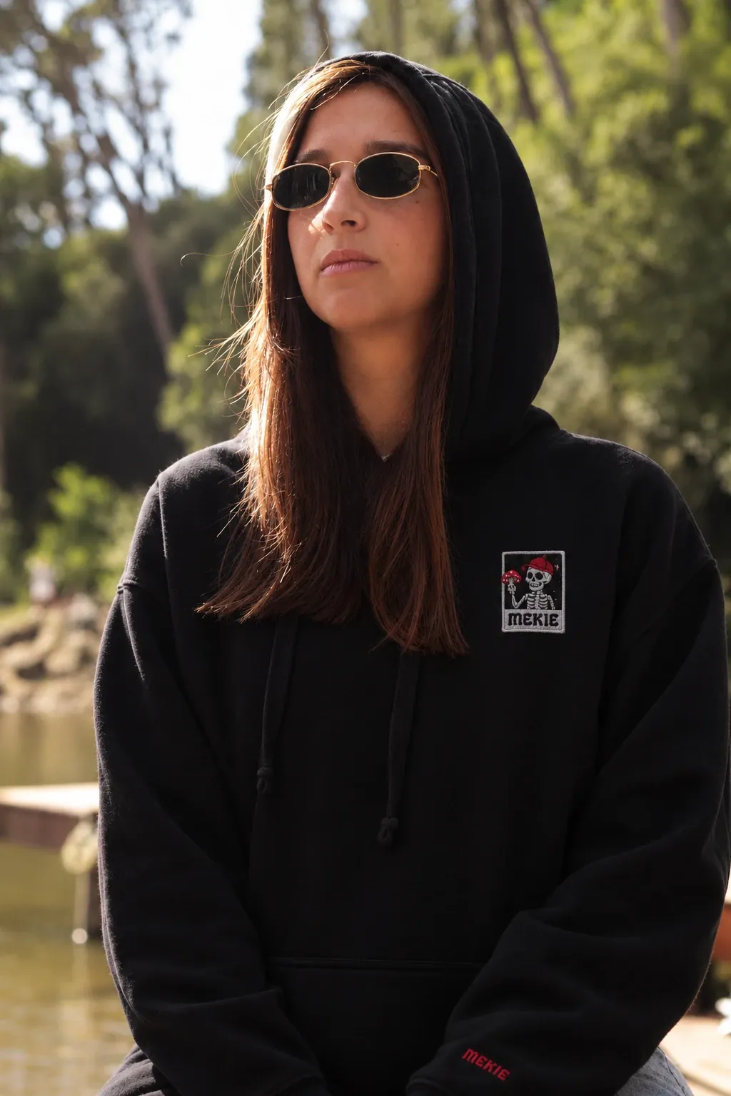 Rapariga de capuz com o hoodie Esqueleto preto, junto ao lago