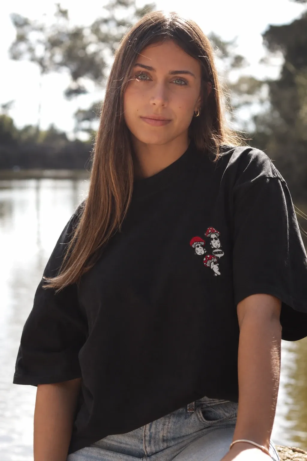 Rapariga com a t-shirt Cogumelos preta junto a um lago